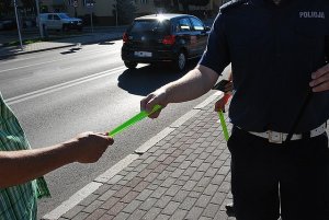 policjant wręcza opaskę odblaskową peszemu