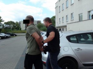 policjant prowadzi zatrzymanego