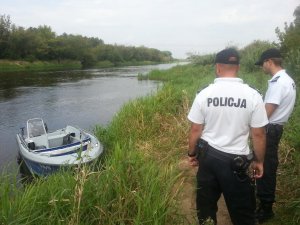 policjanci nad wodą przy łódce