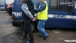 policjant prowadzi zatrzymanego