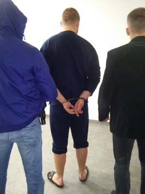 jeden z zatrzymanych prowadzony przez policjantów