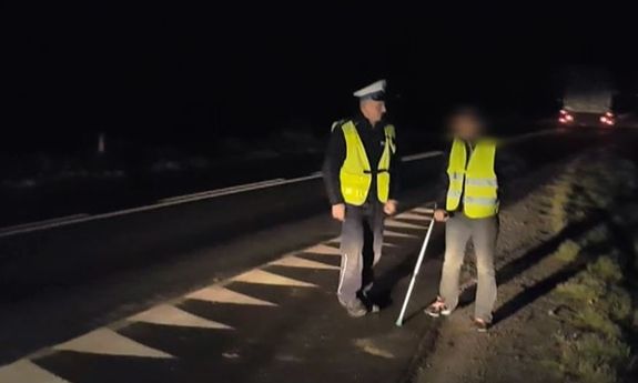 policjant i pieszy w kamizelkach odblaskowych
