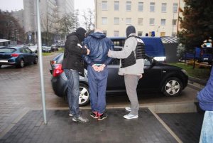 policjanci konwojują zatrzymanego