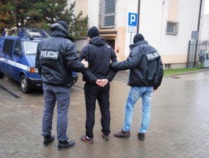 policjanci konwojują zatrzymanego