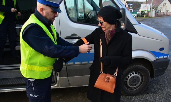 policjant zakłada kobiecie odblaskową opaskę