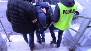 policjanci prowadzą zatrzymanego