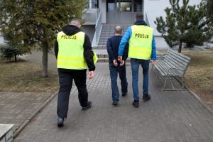 Policjanci prowadzą zatrzymanego