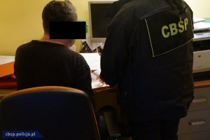 Policjant wykonuje czynności z zatrzymanym