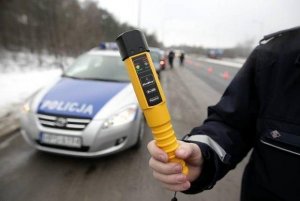 funkcjonariusz z urządzeniem pomiarowym i policyjny radiowóz