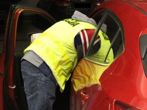 Policjant w trakcie oględzin odzyskanego samochodu