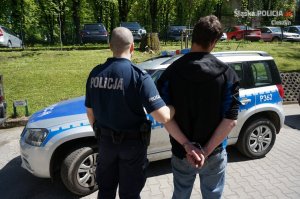 policjant prowadzi zatrzymanego