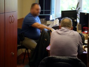 policjant wykonuje czynności z zatrzymanym