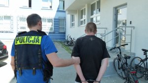 policjant prowadzi zatrzymanego