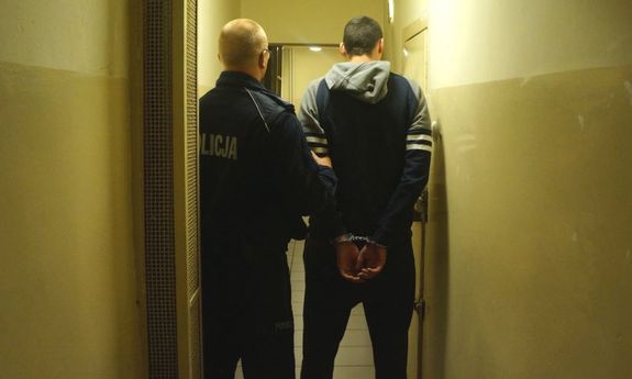 policjant prowadzi zatrzymanego