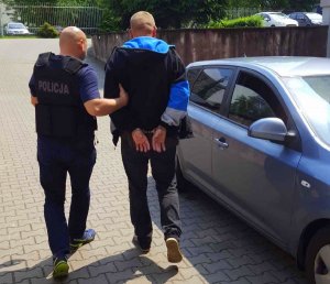 policjant prowadzi zatrzymanego