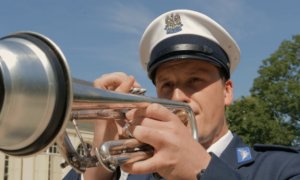 Policjant grający na trąbce - zbliżenie na twarz i instrument