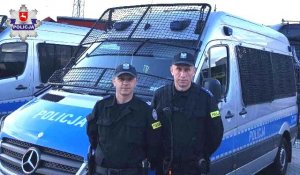Policjanci na tle oznakowanego radiowozu