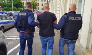 Policjanci prowadzą zatrzymanego