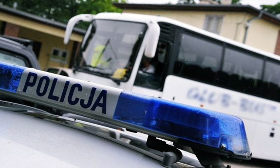 Napis policja na radiowozie, w tle autokar