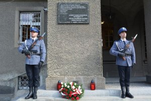 policjanci na warcie przed tablicą upamiętniającą poległych i pomordowanych policjantów II RP