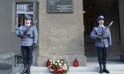 policjanci na warcie przed tablicą upamiętniającą poległych i pomordowanych policjantów II RP
