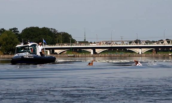 wrocławscy policjanci podczas symulacji akcji ratowniczej na Odrze; od lewej: motorówka z policjantem, tonący mężczyzna, policjant płynący do tonącego z deską ratowniczą