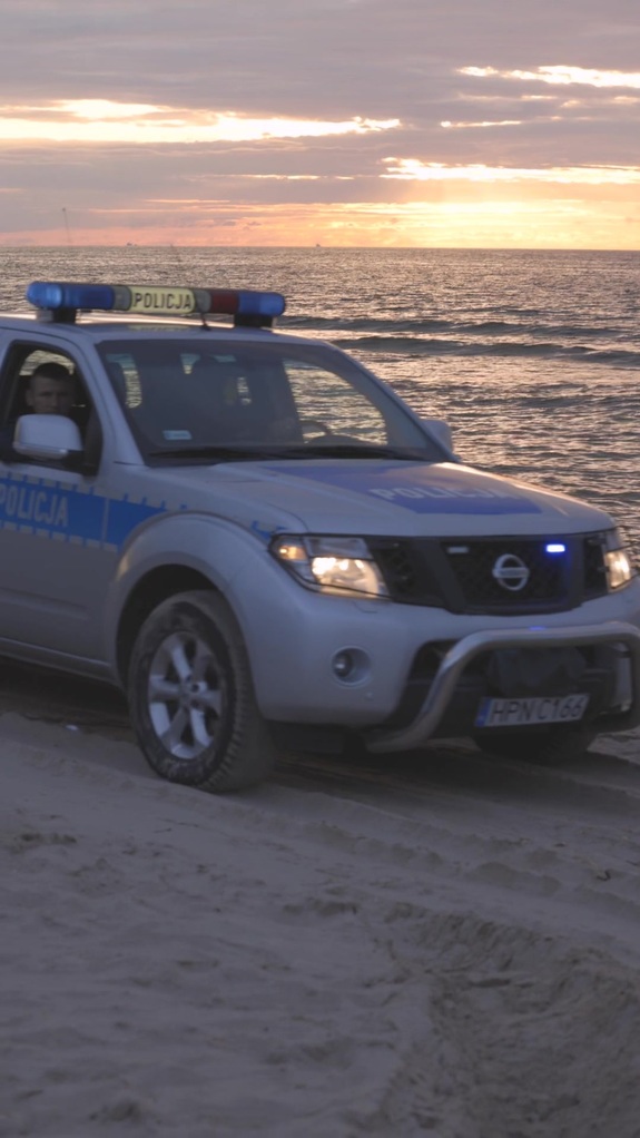 Policyjny radiowóz podczas patrolowania nadmorskiej plaży.