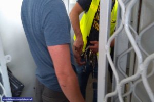 zatrzymany w niebieskiej koszulce podaje ręce do skucia
