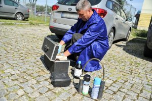 mężczyzna w niebieskim kombinezonie wyjmuje przy aucie urządzenia