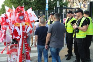 grupa policjantów przed bramą stadionu narodowego patrzy na rzekę przechodzącego tłumu