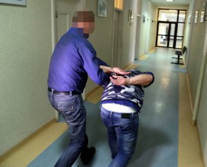 Policjant wykonuje czynności z zatrzymanym