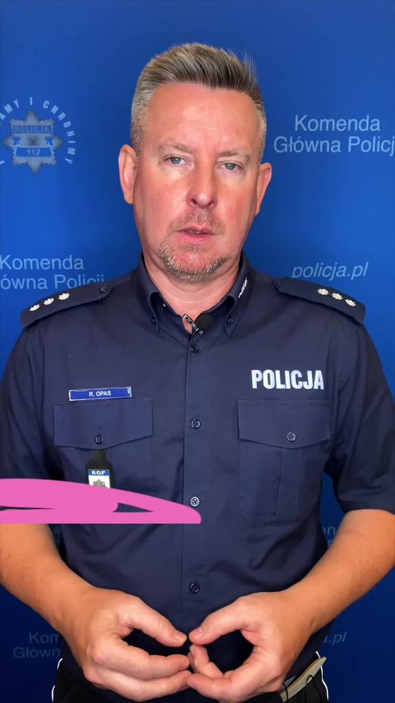 Policjant wypowiada się na tle ścianki reklamowej KGP.