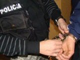 policjant zakłada zatrzymanemu kajdanki