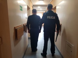 policjant prowadzi zatrzymanego