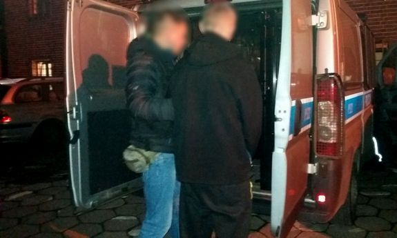 policjant prowadzi zatrzymanego do radiowozu