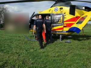 Policjanci wraz z ratownikami umieszczają mężczyzne w śmigłowcu