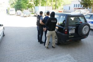 policjanci prowadzą zatrzymanego