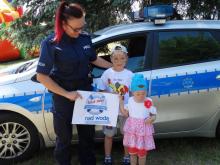 policjantka z dzieckiem na tle radiowozu