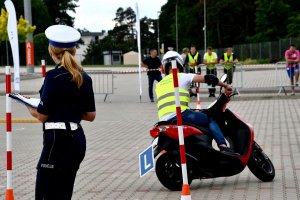 Uczestnik turnieju podczas przejazdu sprawnościowego na skuterze oraz policjantka oceniająca przejazd