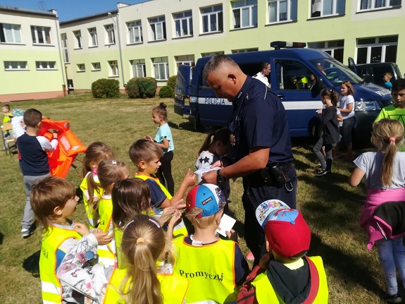 policjant wręcza materiały informacyjne akcji Kręci mnie bezpieczeństwo nad wodą