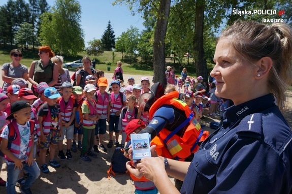 policjantka przekazuje dzieciom materiały informacyjne akcji Kręci mnie bezpieczeństwo nad wodą