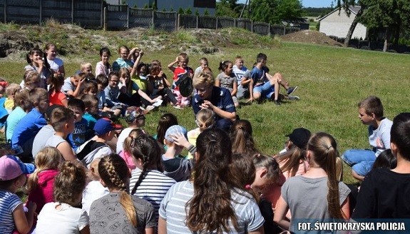 policjant przekazuje dzieciom zasady bezpiecznego zachowania nad wodą