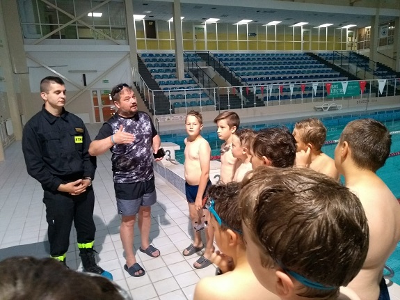 strażak z ratownikiem przekazuj dzieciom zasady bezpiecznego zachowania nad wodą