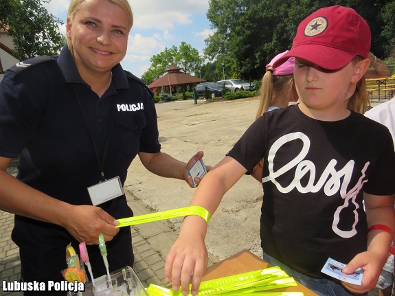 policjantka przekazuje dzieciom gadżety związane z bezpieczeństwem nad wodą