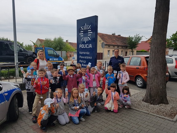 policjantka wraz z dziećmi trzymającymi ulotki akcji Kręci mnie bezpieczeństwo nad wodą