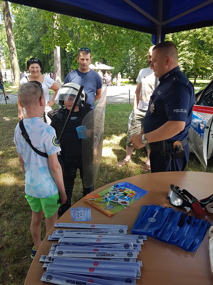 policjant wręcza dziecku materiały informacyjne akcji Kręci mnie bezpieczeństwo nad wodą
