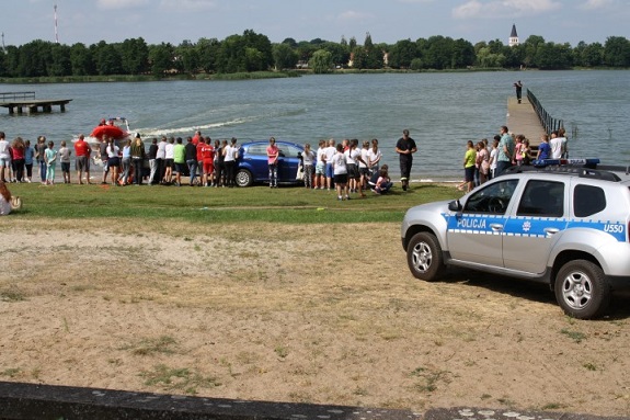 Policjanci na plaży przekazują zasady bezpiecznego chowania nad wodą