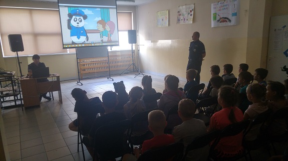 Policjant przekazuje dzieciom zasady bezpiecznego zachowania nad wodą