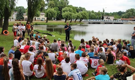 Policjant przekazuje dzieciom zasady bezpiecznego zachowania nad wodą
