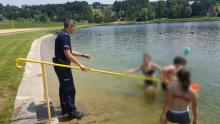 policjant wręcza dziewczynie gadżety związane z akcją Kręci mnie bezpieczeństwo nad wodą